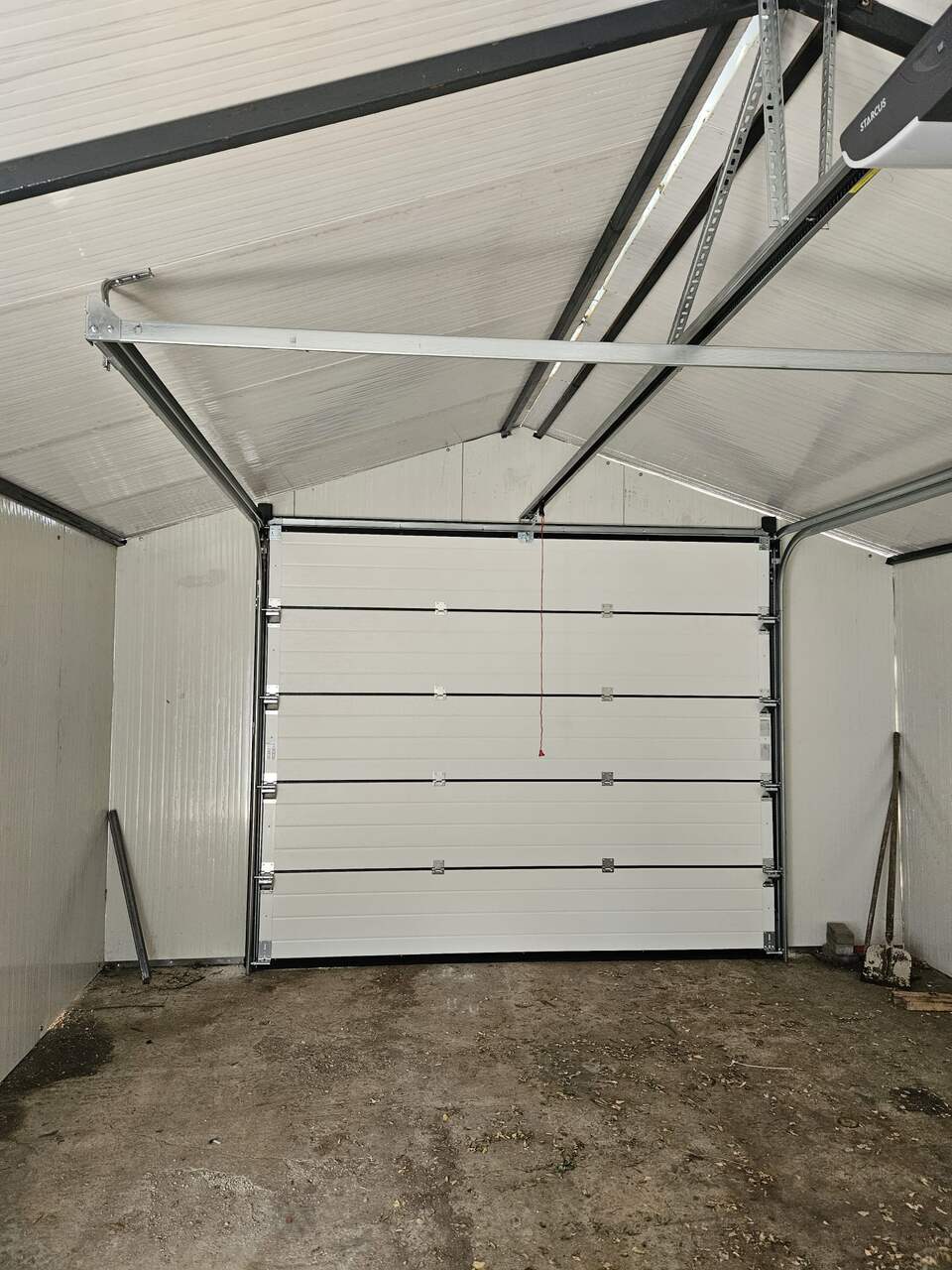 Ușă de garaj secțională văzută din interior, cu automatizare montată sub acoperiș