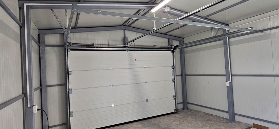 Garaj pe structură metalică văzut din interior, cu ușă de garaj secțională, arcuri de torsiune și automatizare