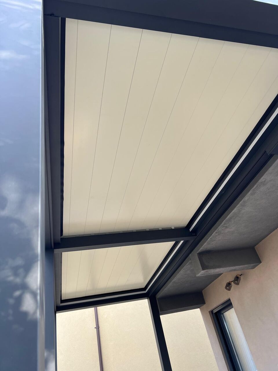 Lamelele închise ale unei pergole din aluminiu cu structură antracit, văzute de dedesubt